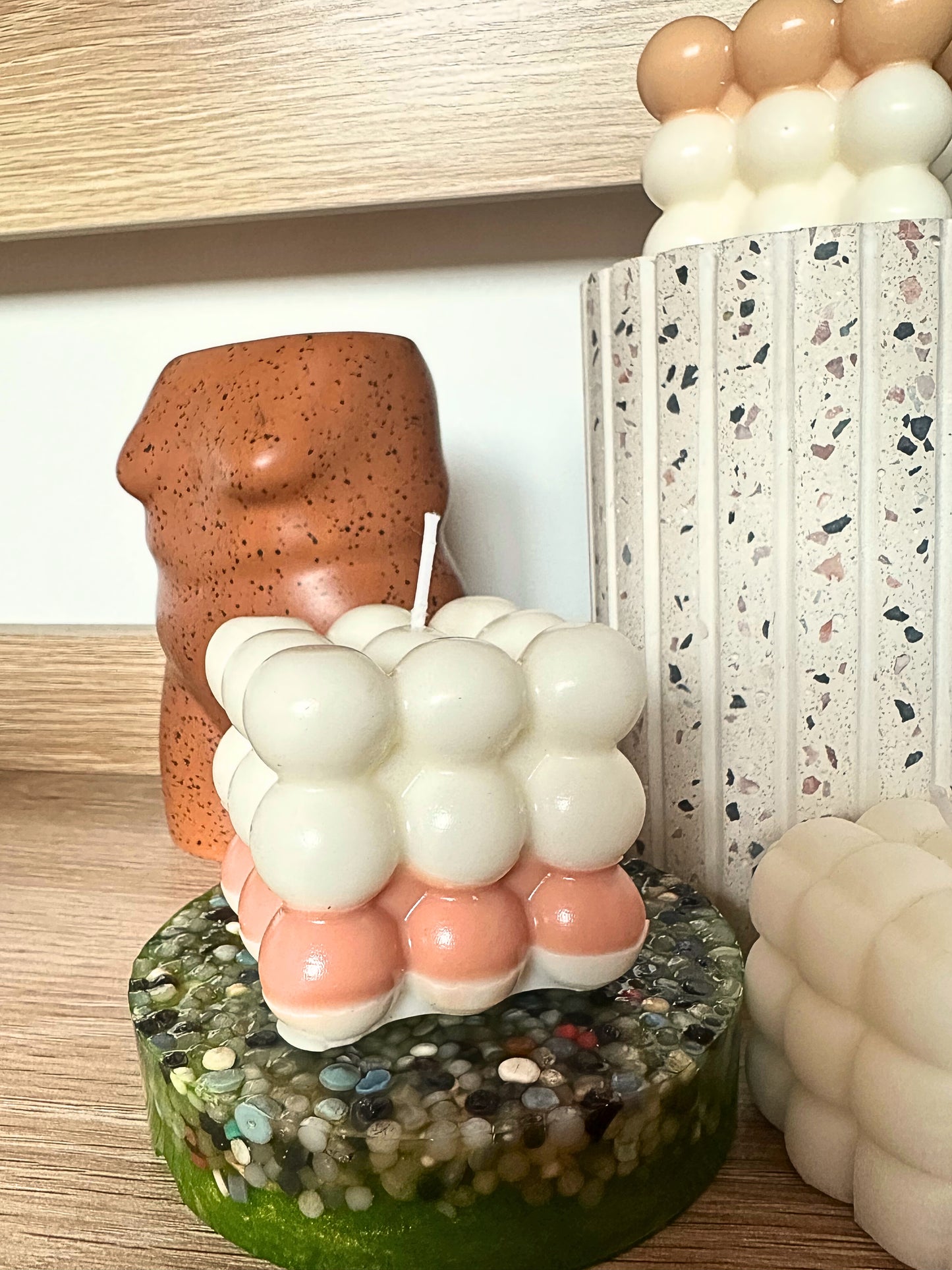 Cylindrical candle with bubble design on a textured base, surrounded by balloons.