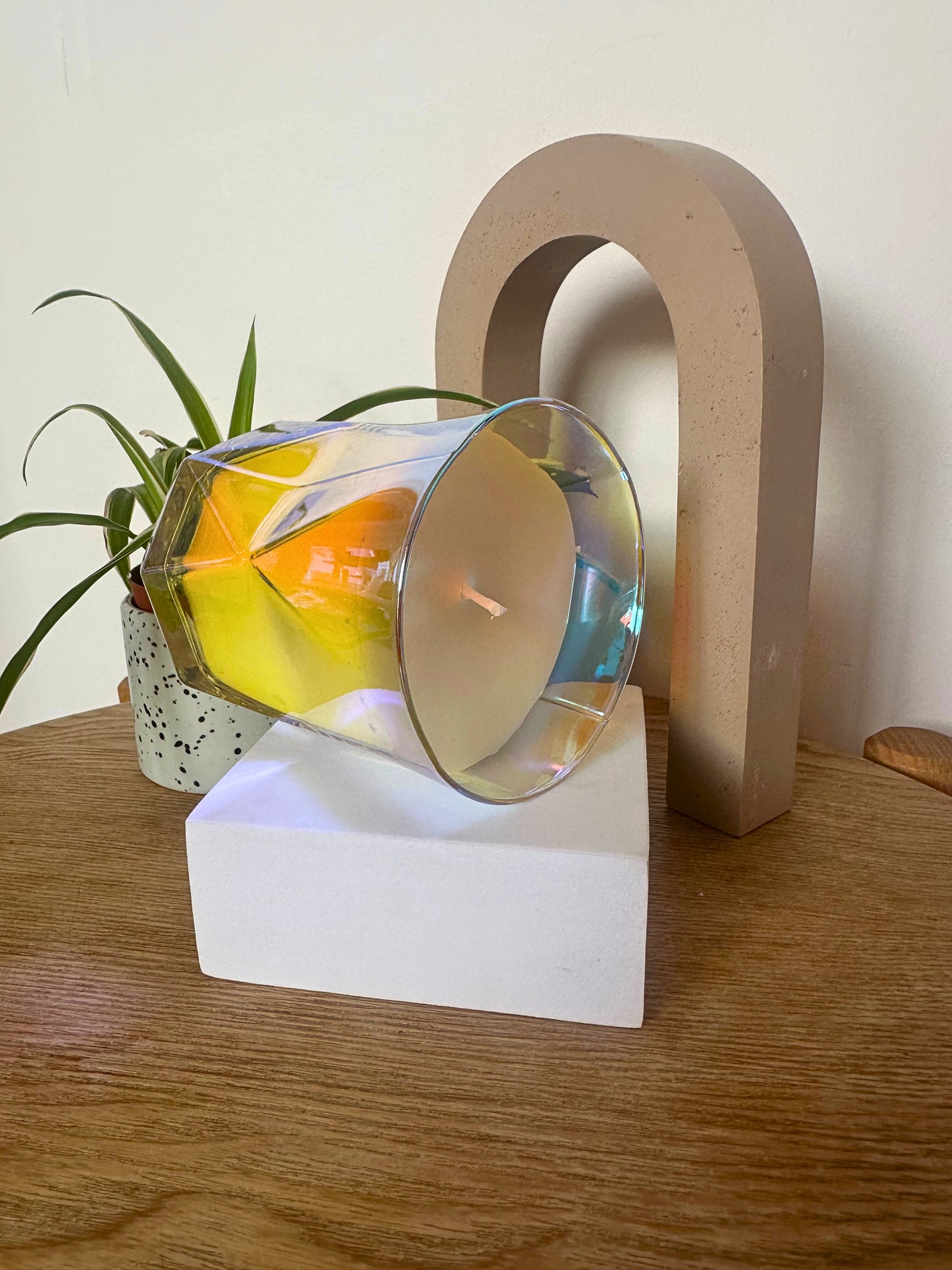 Decorative Suki Home The Hikari Candle in Crystal piece on a white base with a wooden arch in the background.
