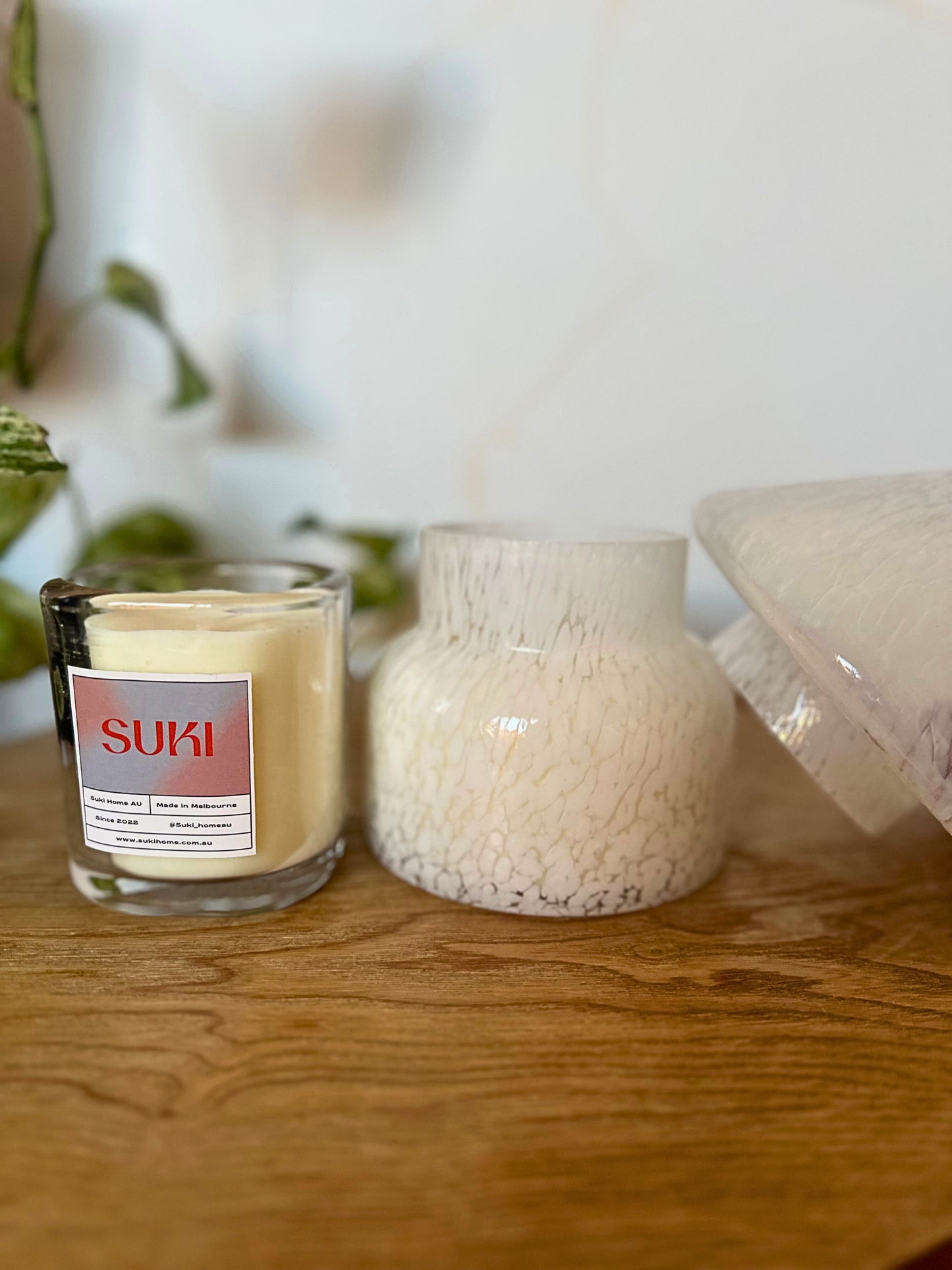 Candle with a 'SUKI' label on a wooden surface