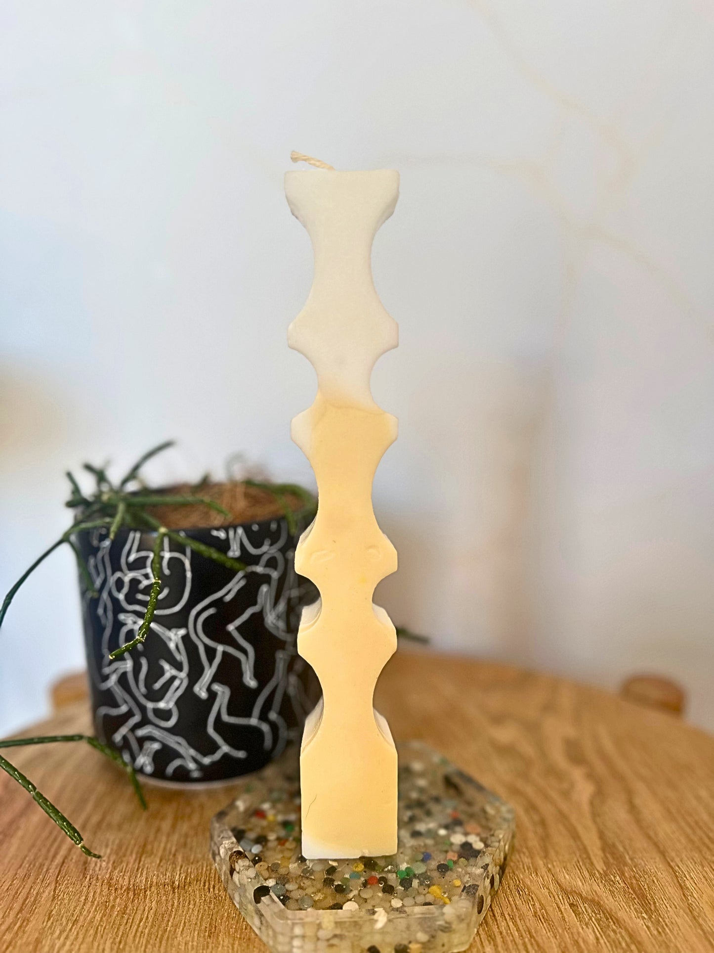 Decorative candle with wavy design on a textured base, with a blurred background