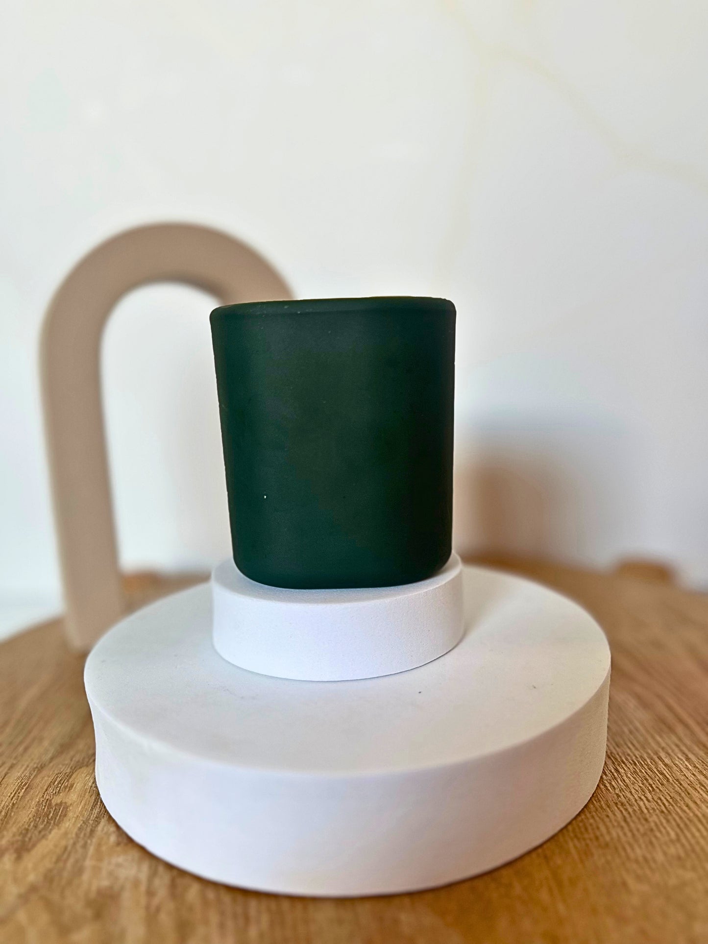 Dark green cup on a white base with a beige chair in the background