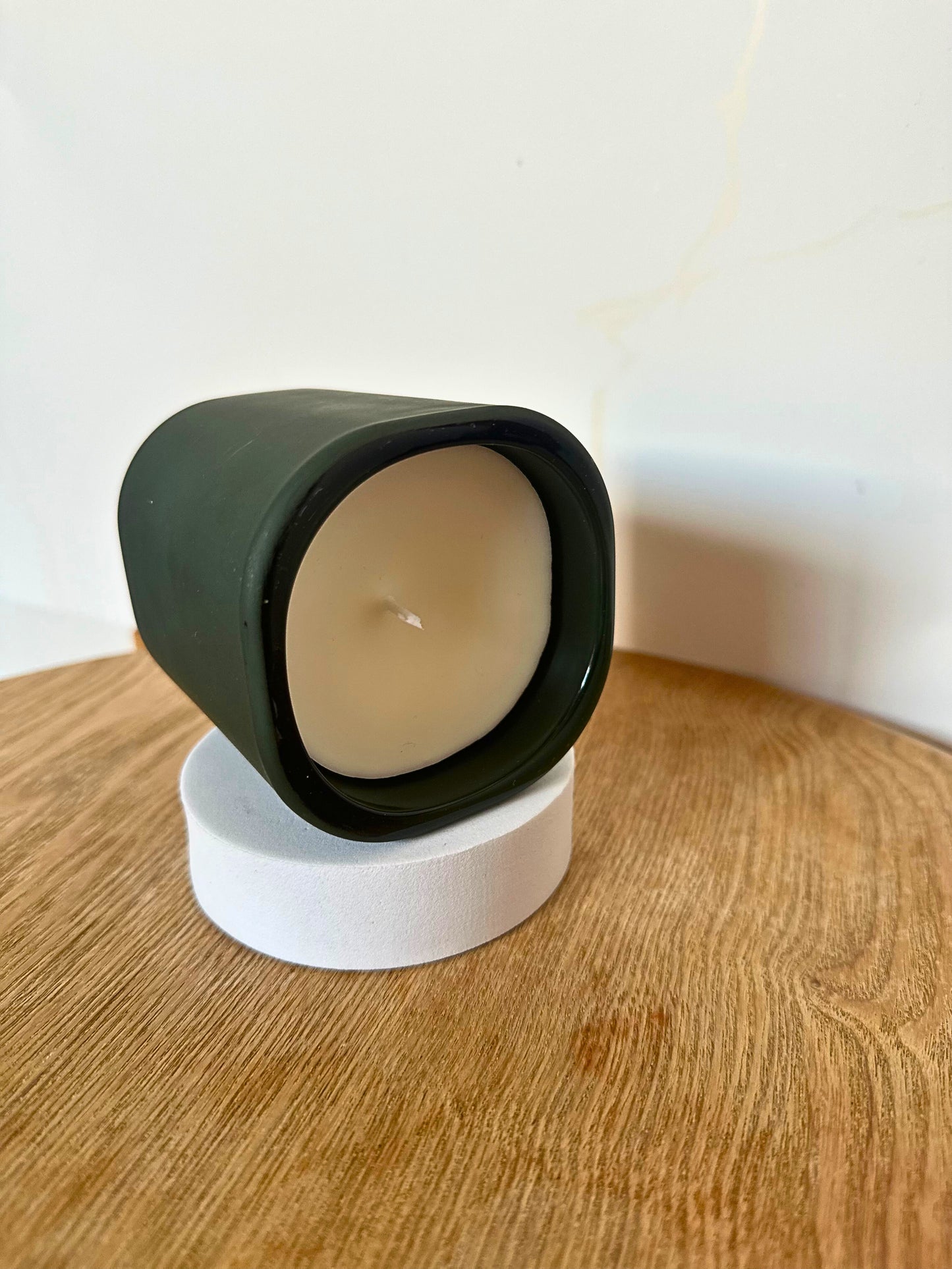 Candle in a green holder on a wooden surface with a white background