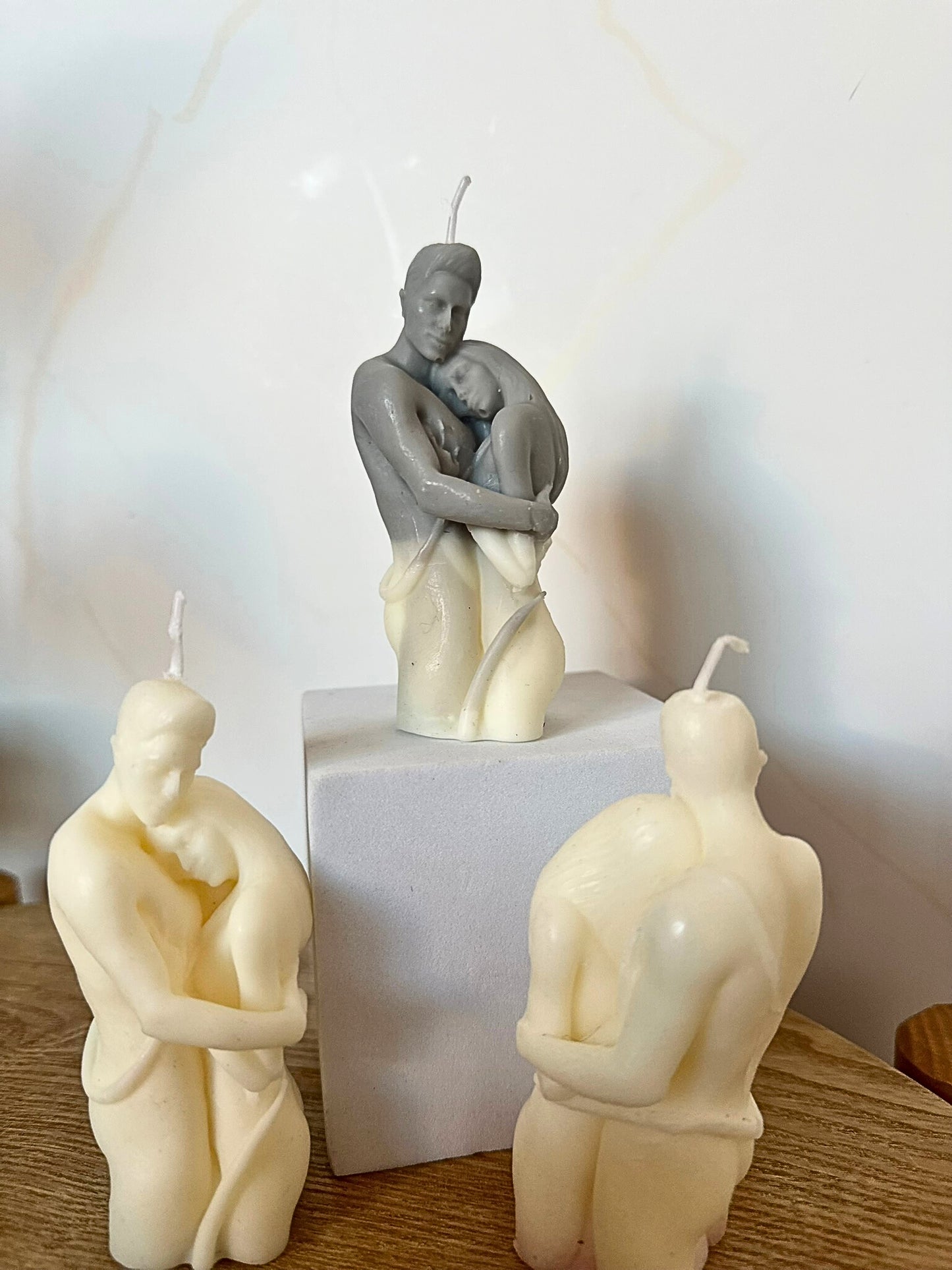 Three candle sculptures of a thinker in a minimal indoor setting