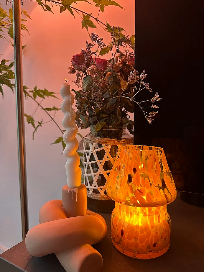 Decorative setup with the Mini Mushroom Candle Lamp in Orange lit on display with a pillar candle