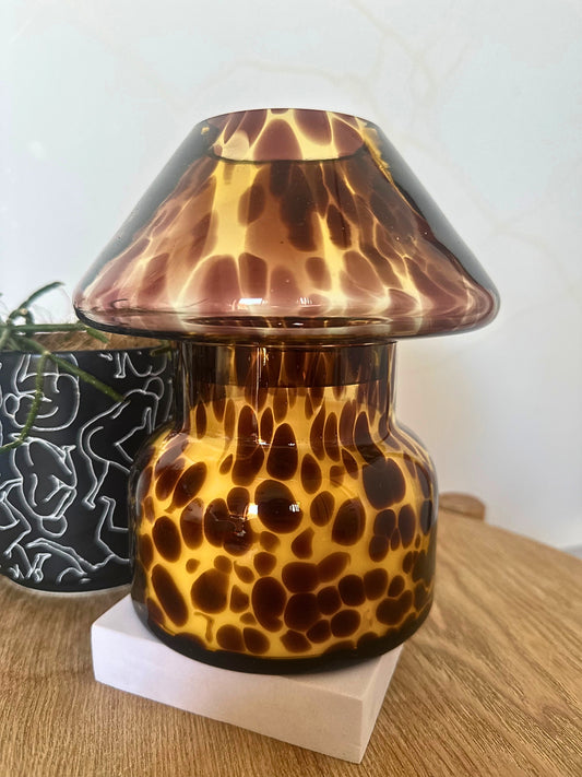 Tortoiseshell-patterned glass lamp on a wooden surface with a white background