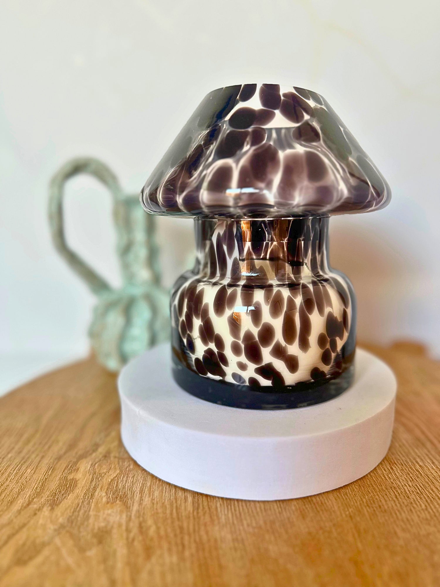 Suki Home Mushroom Candle Lamp in Black on Display on a white base, placed on a wooden table.