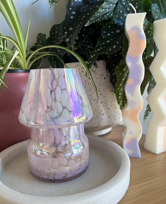 The Mini Mushroom Candle Lamp in Pink on display with plants and pillar candles