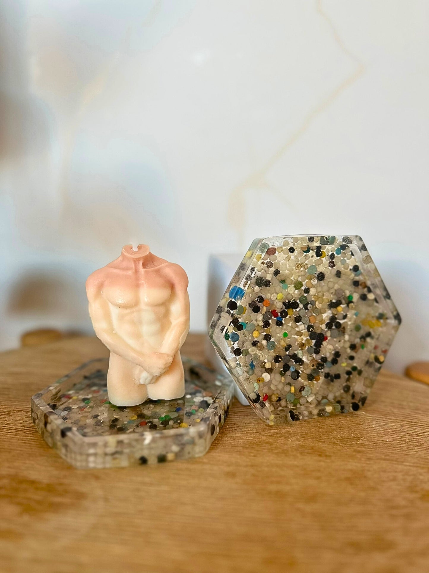 Small figurine of a person in a praying position on a textured surface with a hexagonal crystal container.