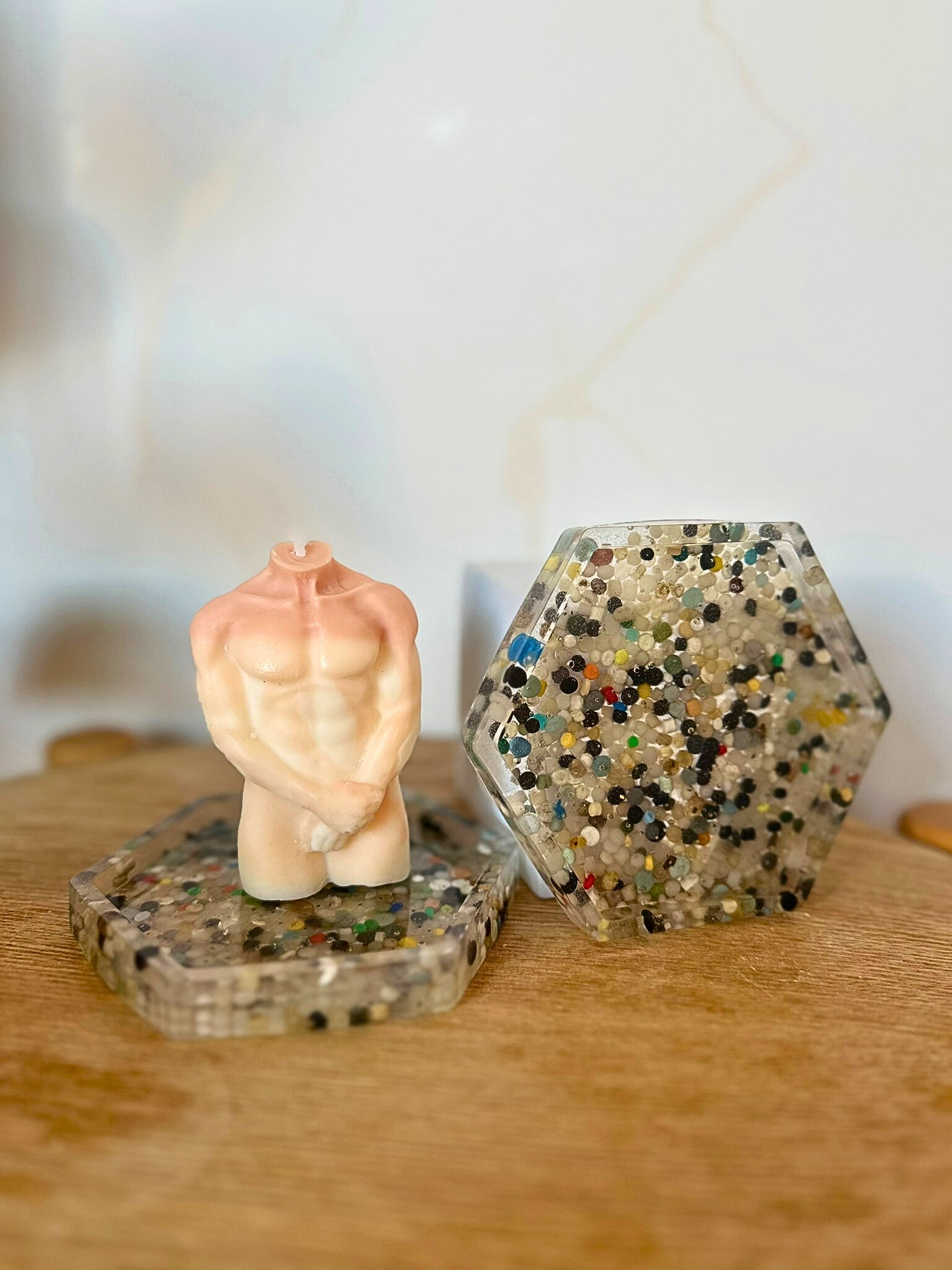 Small figurine of a person in a praying position on a textured surface with a hexagonal crystal container.