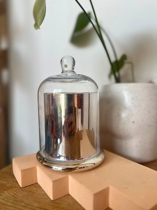 Suki Home The Seina Cloche Candle in Large Silver on a wooden block with a blurred background
