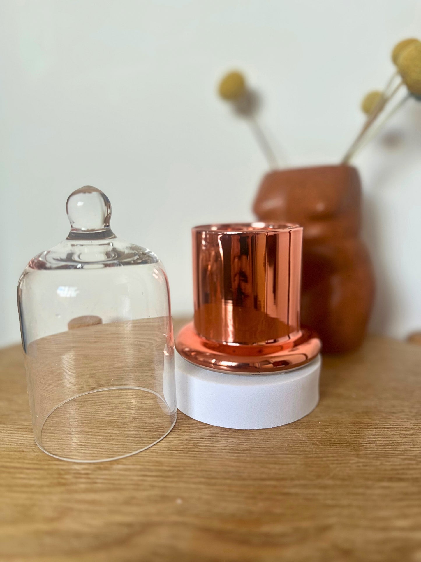 Suki Home The Seina Cloche Candle in Small Gold, and white base on a wooden surface.