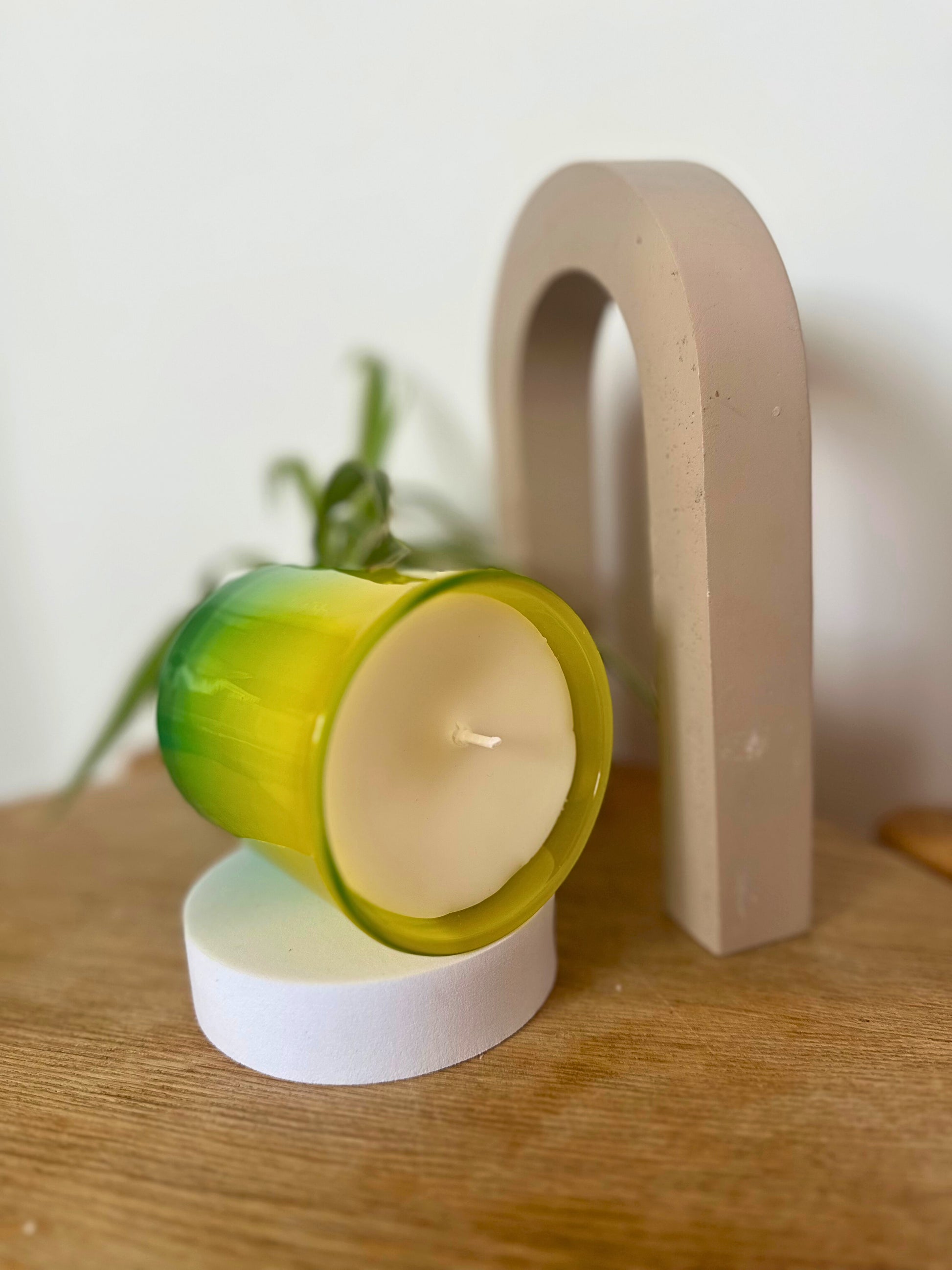 The Midori Candle by Suki Home on display on a wooden surface with a blurred background