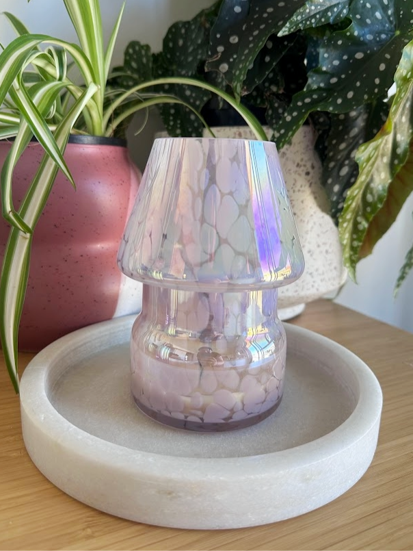 The Mini Mushroom Candle Lamp in Pink on display with plants