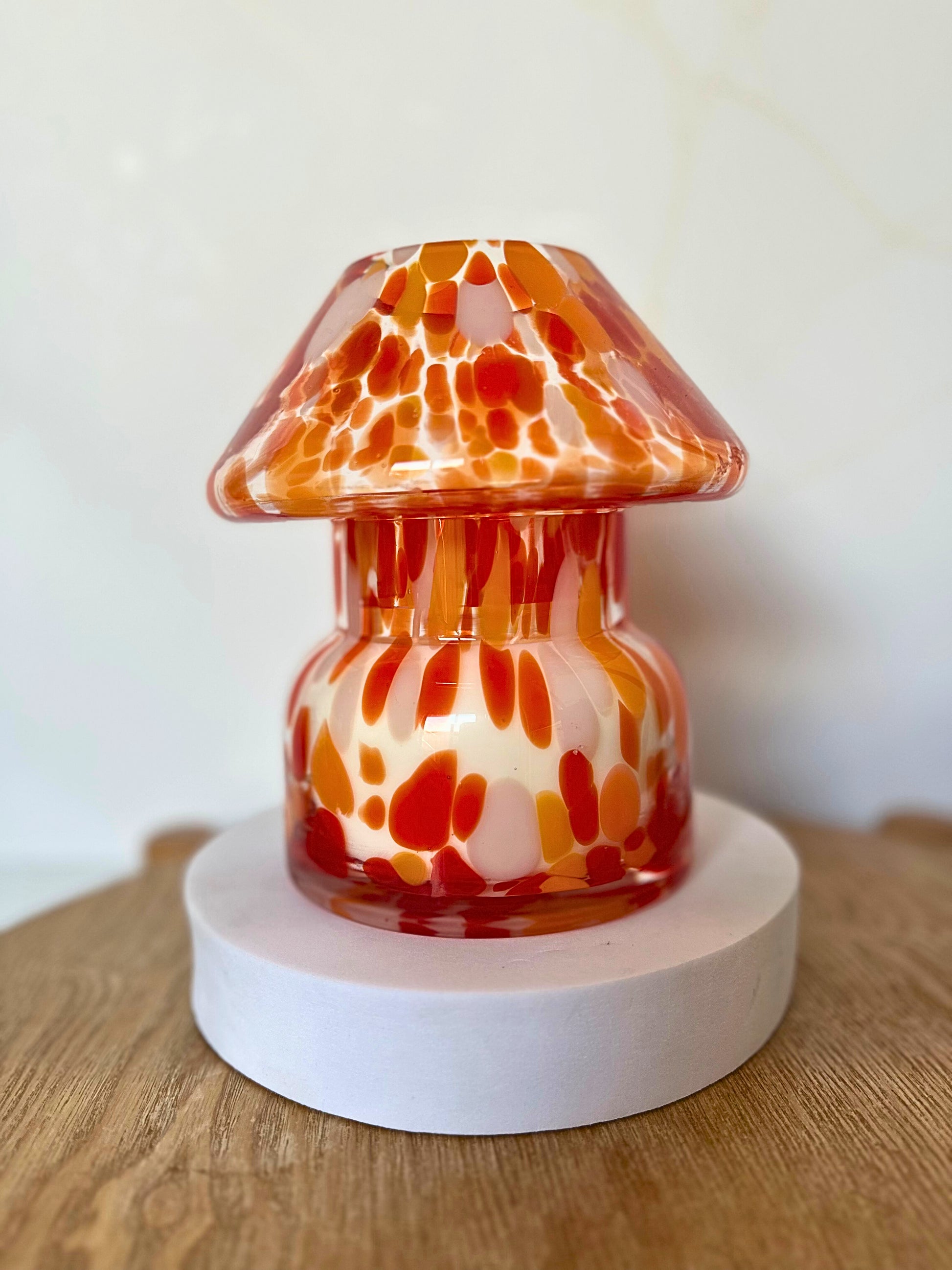 Decorative glass lamp with orange and white pattern on a wooden surface