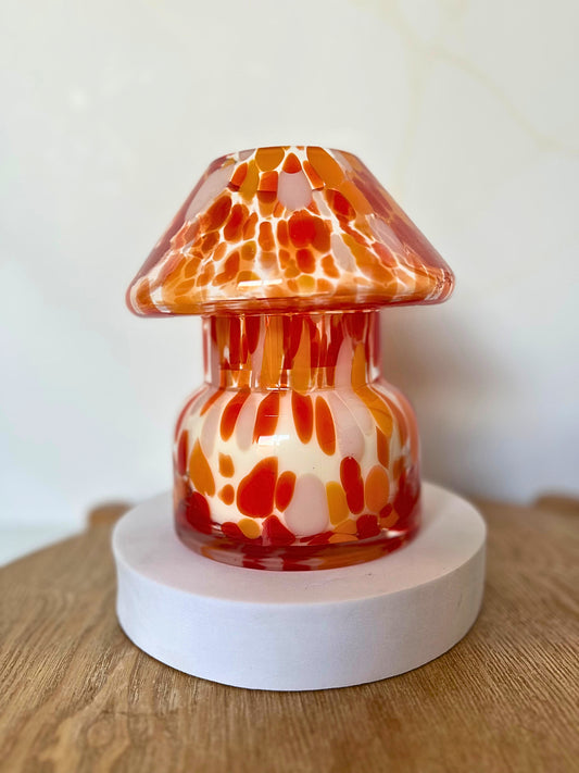 Decorative glass lamp with orange and white pattern on a wooden surface