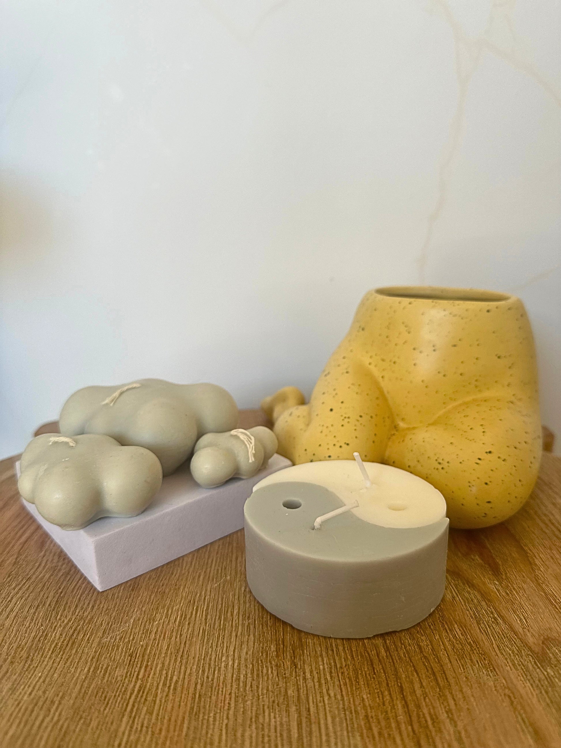 Set of candles including a yellow textured vase on a wooden surface.